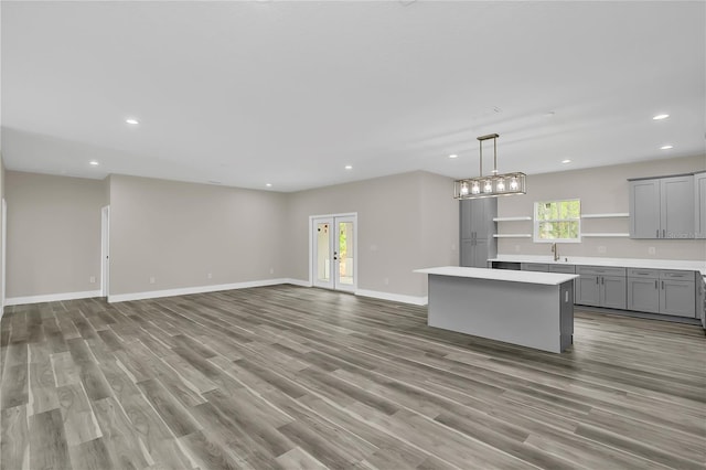 kitchen with a center island, gray cabinets, light countertops, open floor plan, and baseboards