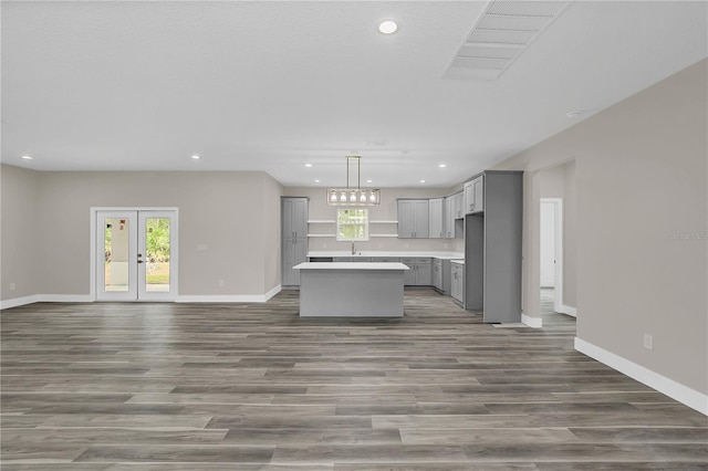 kitchen featuring a center island, light countertops, hanging light fixtures, gray cabinetry, and open floor plan