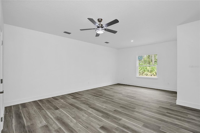 spare room with ceiling fan, wood finished floors, visible vents, and baseboards