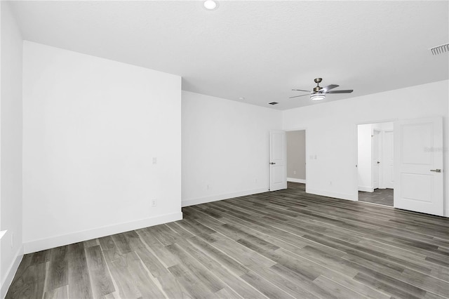 spare room featuring a textured ceiling, ceiling fan, wood finished floors, visible vents, and baseboards