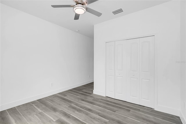 unfurnished bedroom featuring a closet, visible vents, a ceiling fan, wood finished floors, and baseboards