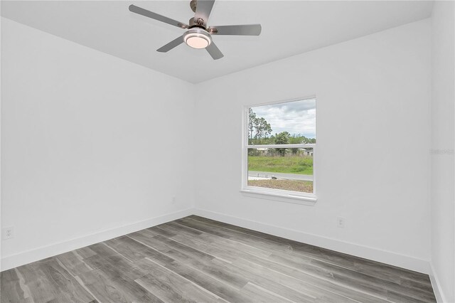 spare room featuring ceiling fan, baseboards, and wood finished floors