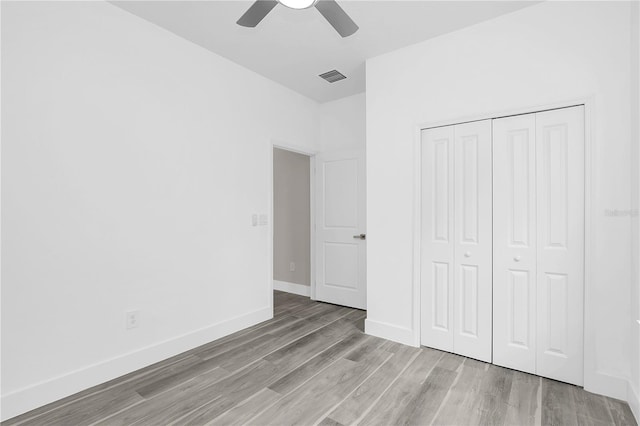 unfurnished bedroom featuring a closet, visible vents, light wood-style flooring, ceiling fan, and baseboards