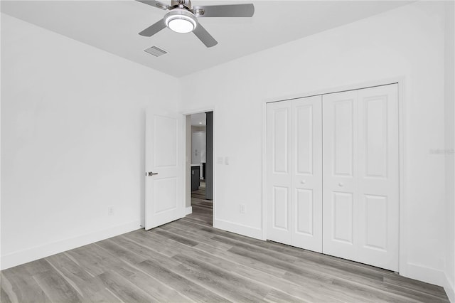 unfurnished bedroom featuring visible vents, a closet, light wood-style flooring, and baseboards