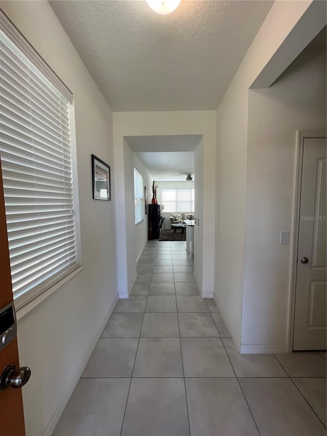 hallway featuring light tile patterned flooring and a textured ceiling