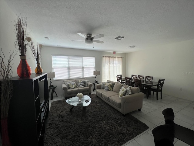 tiled living room featuring ceiling fan and a textured ceiling