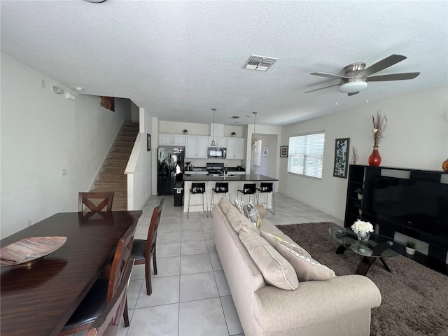 tiled living room featuring ceiling fan and a textured ceiling