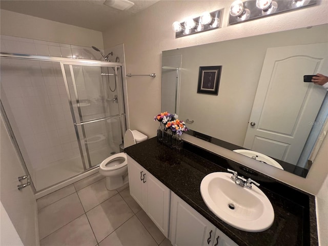 bathroom with tile patterned flooring, vanity, toilet, and a shower with door