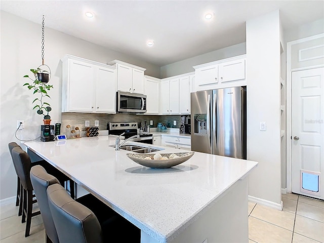 kitchen featuring white cabinets, kitchen peninsula, stainless steel appliances, and tasteful backsplash