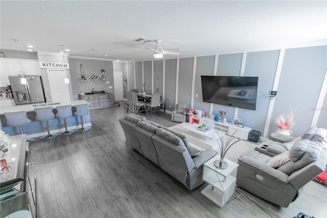 living room with sink, hardwood / wood-style flooring, ornamental molding, and ceiling fan