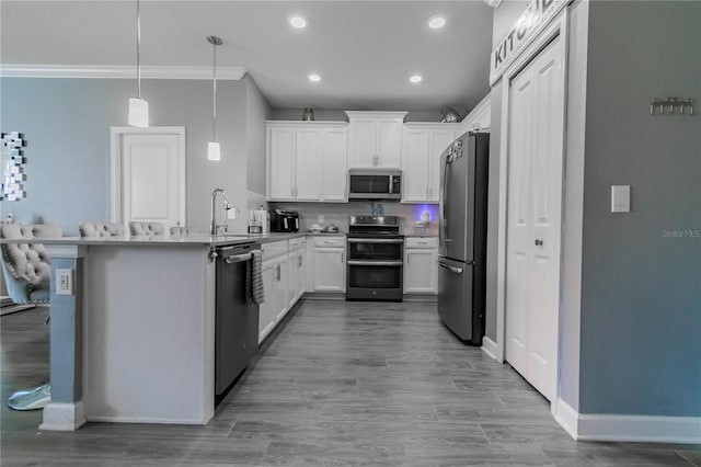 kitchen with kitchen peninsula, stainless steel appliances, hanging light fixtures, white cabinetry, and ornamental molding