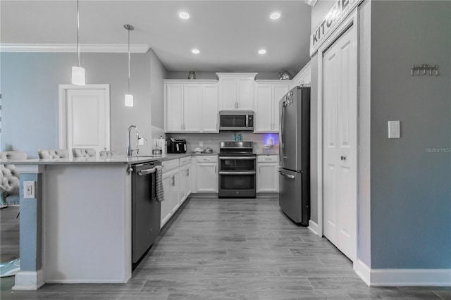 kitchen with hanging light fixtures, light wood-type flooring, appliances with stainless steel finishes, white cabinets, and kitchen peninsula