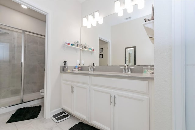 bathroom with vanity with extensive cabinet space, toilet, a shower with shower door, tile flooring, and double sink