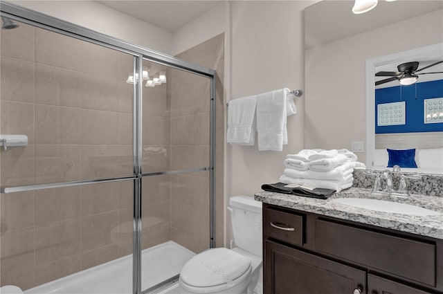 bathroom with ceiling fan, vanity, toilet, and a shower with shower door