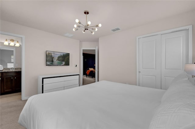 carpeted bedroom with ensuite bathroom, a closet, and a chandelier