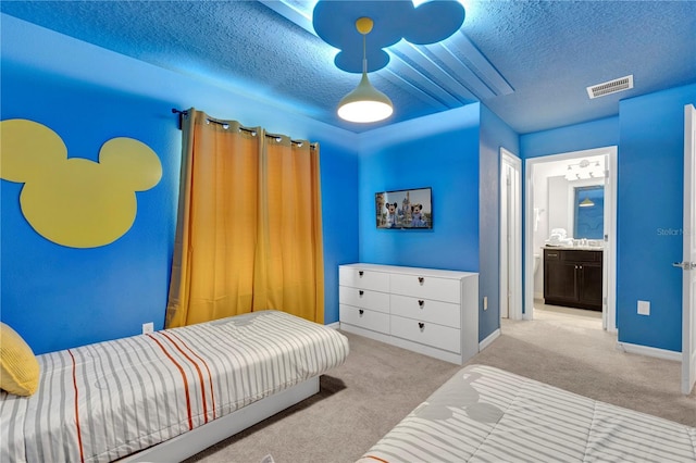 bedroom with a textured ceiling, connected bathroom, and light colored carpet