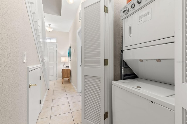 laundry room with light tile patterned floors and stacked washer / dryer