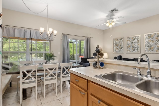 kitchen featuring sink, light tile patterned floors, hanging light fixtures, and ceiling fan with notable chandelier