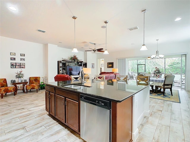 kitchen featuring sink, a kitchen island with sink, hanging light fixtures, dark stone countertops, and stainless steel dishwasher