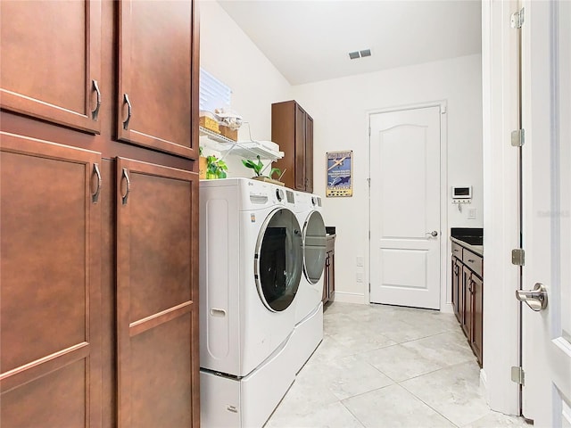 laundry area featuring light tile patterned flooring, cabinets, and washing machine and dryer