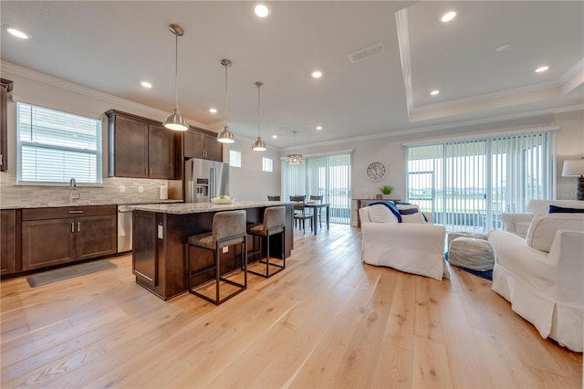 kitchen featuring a kitchen breakfast bar, stainless steel appliances, pendant lighting, a center island, and light hardwood / wood-style floors