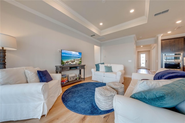 living room with light hardwood / wood-style flooring, a raised ceiling, and ornamental molding