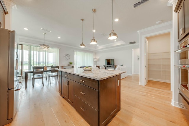 kitchen featuring light stone countertops, crown molding, decorative light fixtures, a kitchen island, and appliances with stainless steel finishes