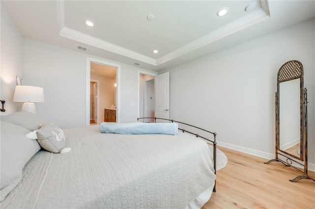 bedroom featuring a raised ceiling, connected bathroom, crown molding, and light wood-type flooring