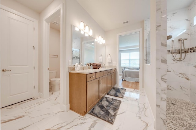 bathroom with toilet, vanity, and tiled shower