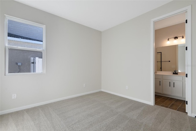 unfurnished bedroom featuring ensuite bath and carpet