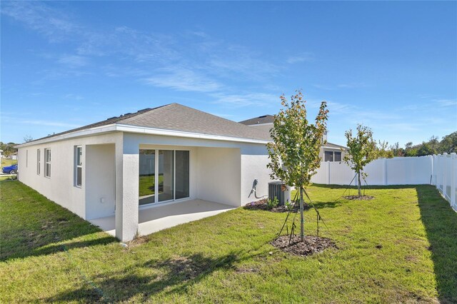 rear view of house featuring a yard and central air condition unit