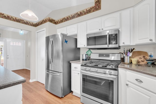 kitchen featuring hanging light fixtures, appliances with stainless steel finishes, vaulted ceiling, white cabinets, and light wood-type flooring