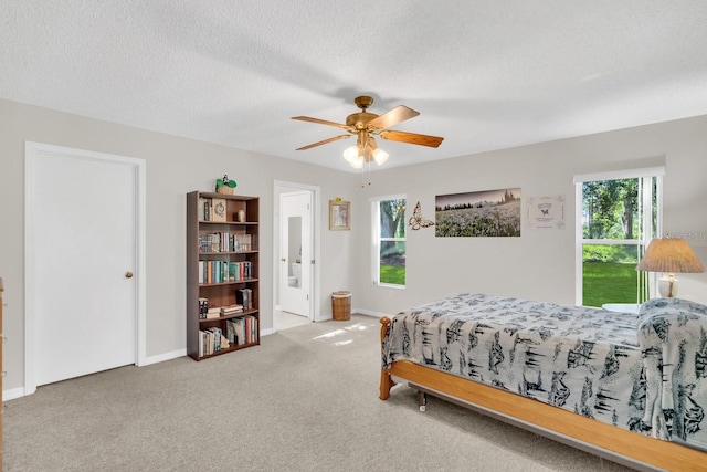 bedroom with multiple windows, ceiling fan, carpet, and a textured ceiling