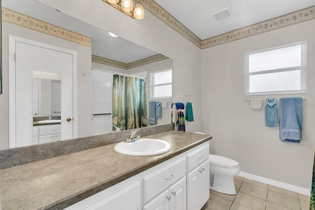 bathroom with toilet, vanity, and tile patterned floors