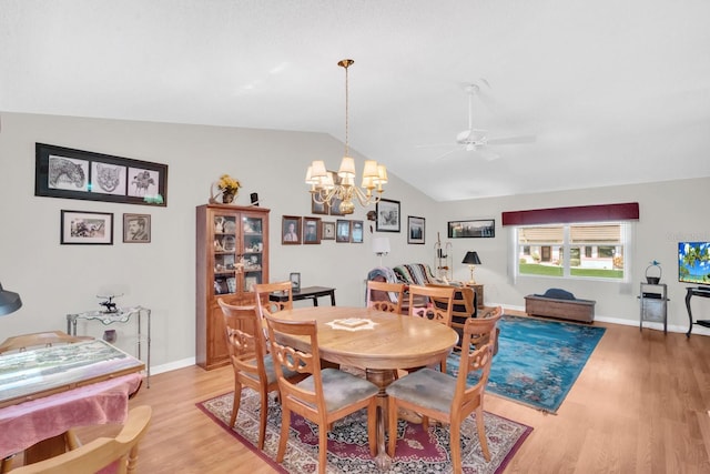 dining area with ceiling fan with notable chandelier, light wood-type flooring, and lofted ceiling