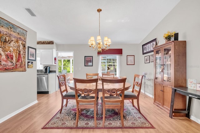 dining space with a chandelier, light hardwood / wood-style floors, and vaulted ceiling