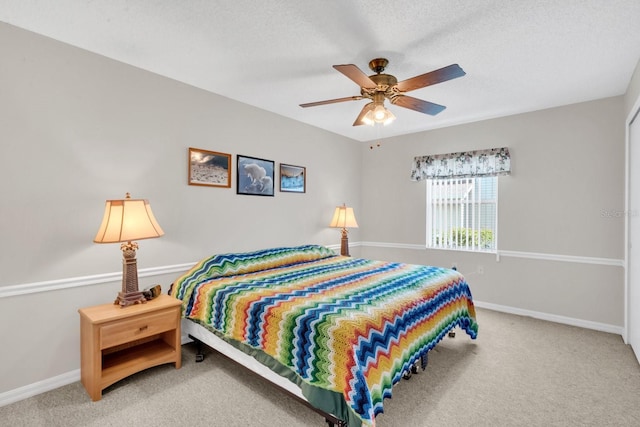 carpeted bedroom with ceiling fan and a textured ceiling