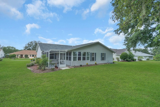 rear view of house with a sunroom and a lawn