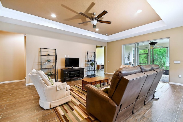 living room featuring light hardwood / wood-style floors, a raised ceiling, and ceiling fan