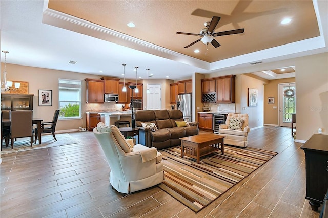 living room with light hardwood / wood-style floors, beverage cooler, and a tray ceiling