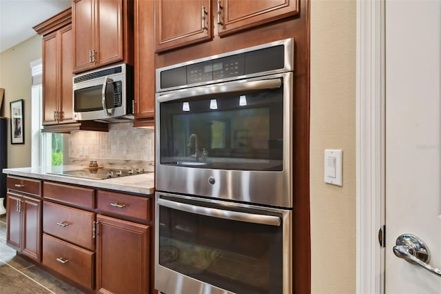 kitchen with backsplash, light stone counters, stainless steel appliances, and dark tile patterned flooring