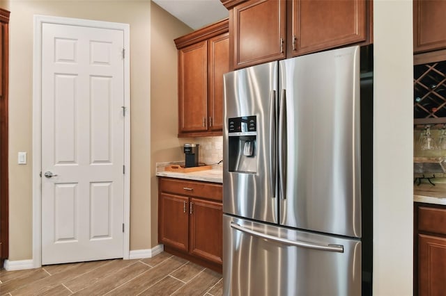 kitchen with light stone countertops, decorative backsplash, wood-type flooring, and stainless steel fridge with ice dispenser