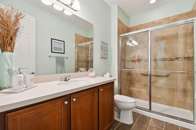 bathroom featuring vanity, toilet, and a shower with shower door