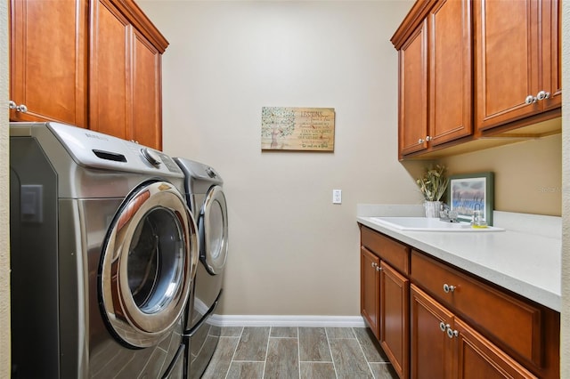 laundry area with independent washer and dryer, cabinets, wood-type flooring, and sink