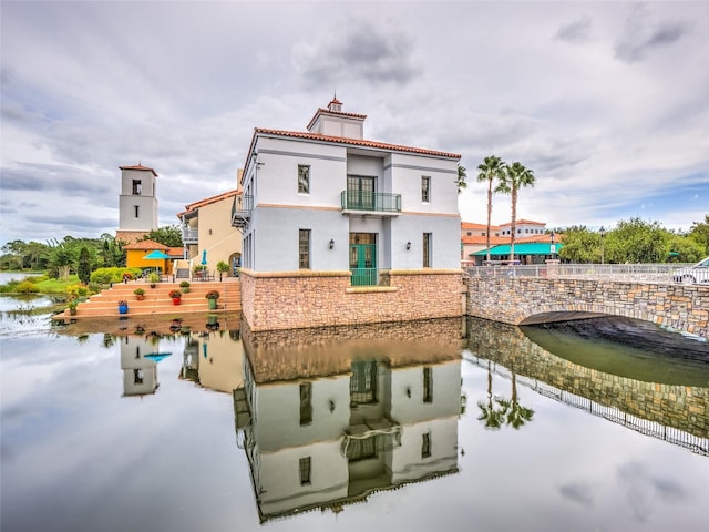 rear view of property featuring a balcony and a water view