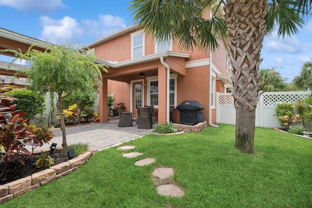 back of property featuring a yard, ceiling fan, and a patio area