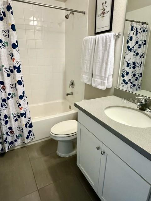 full bathroom featuring toilet, tile patterned floors, vanity, and shower / tub combo with curtain