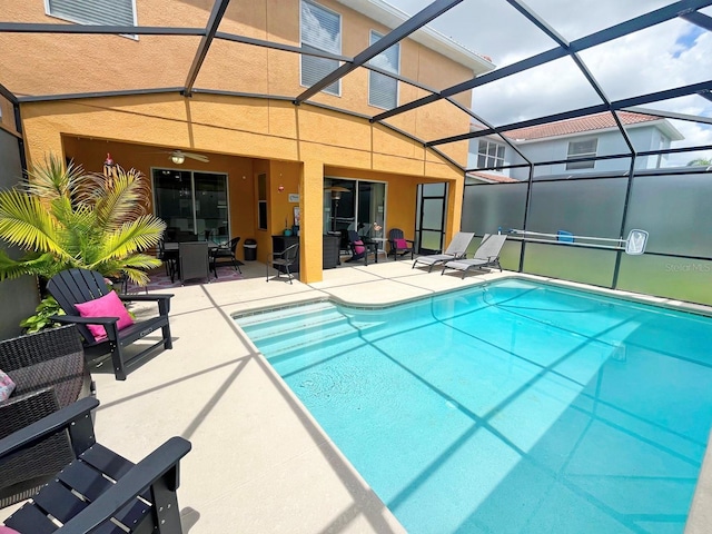 view of pool with glass enclosure, ceiling fan, and a patio