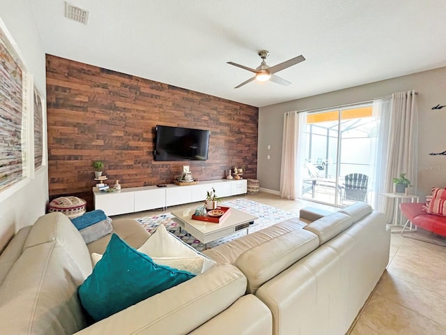 living room with light tile patterned floors, ceiling fan, and wooden walls