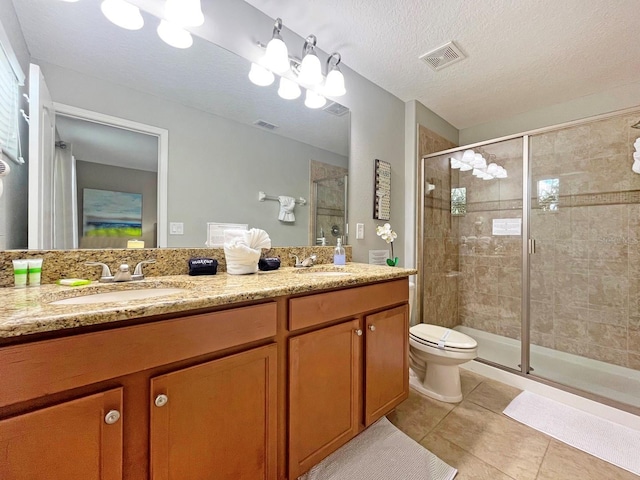 bathroom with a shower with door, vanity, a textured ceiling, and tile patterned flooring